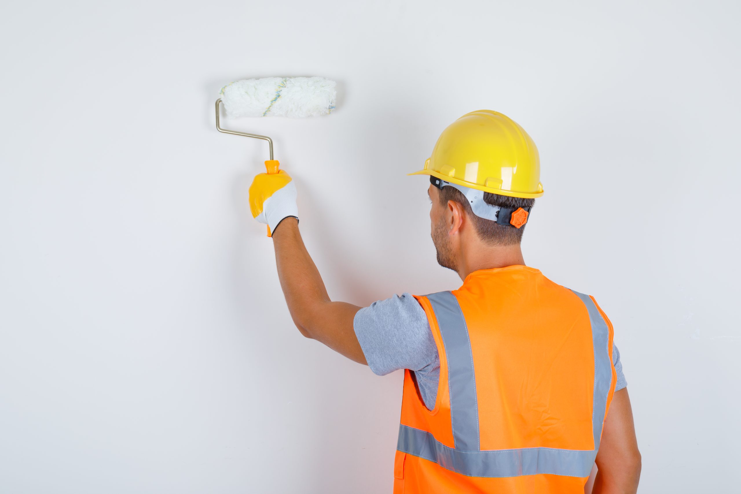 male builder uniform helmet gloves painting wall with roller back view scaled-hayward-california